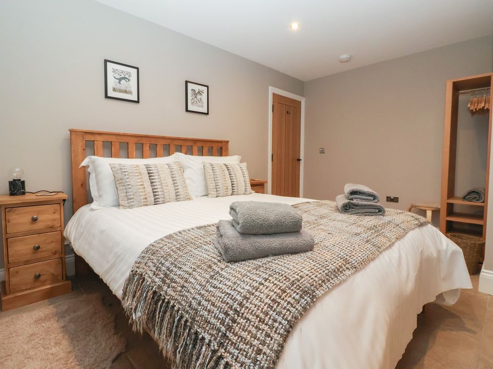 A bedroom with a bed and bedside table at Stable End Cottage, York