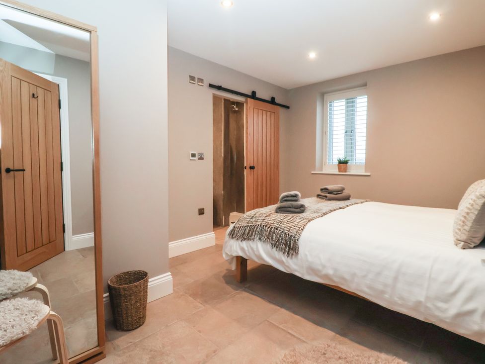 A bedroom with a bed and towels on the side at Stable End Cottage in York