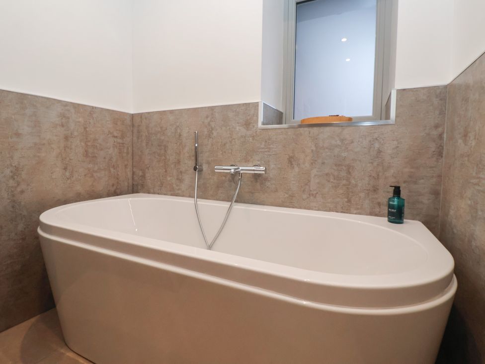 A bathtub and a window in a bathroom at Stable End Cottage in York