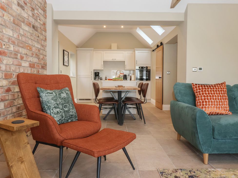 A living room with an armchair and dining table at Stable End Cottage Cuckoo Nest Farm near Wilberfoss