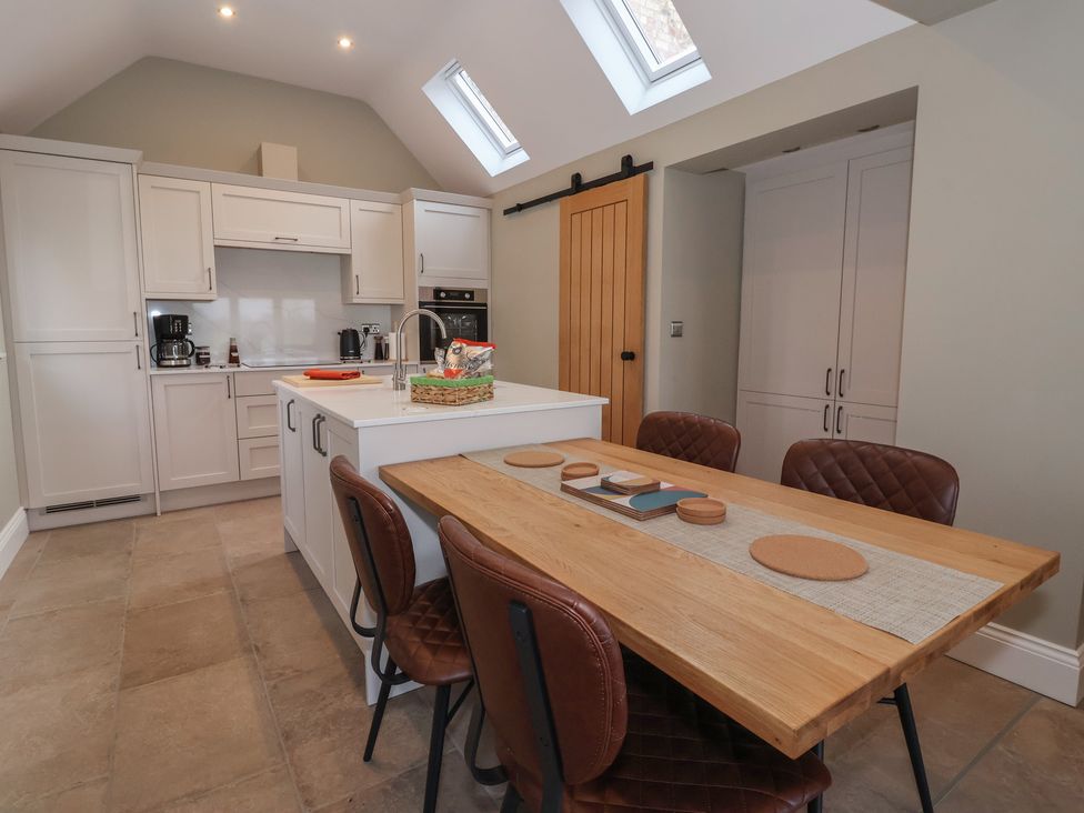 A kitchen with cabinets and dining table at Stable End Cottage near Cuckoo Nest Farm
