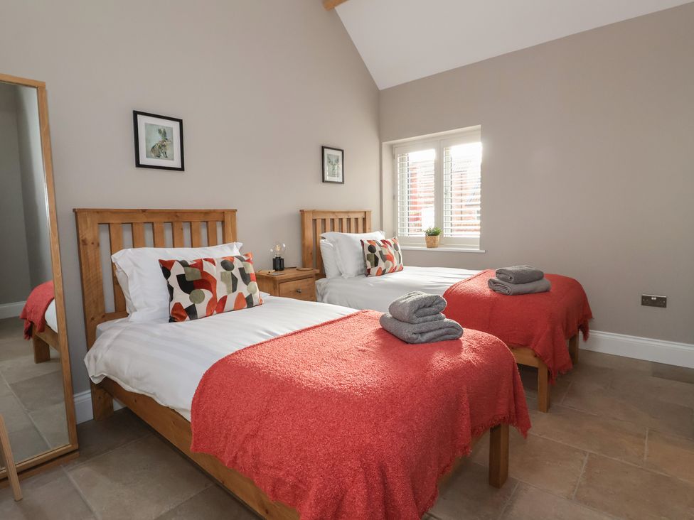 A bedroom with two beds and a mirror at Stable End Cottage near Cuckoo Nest Farm