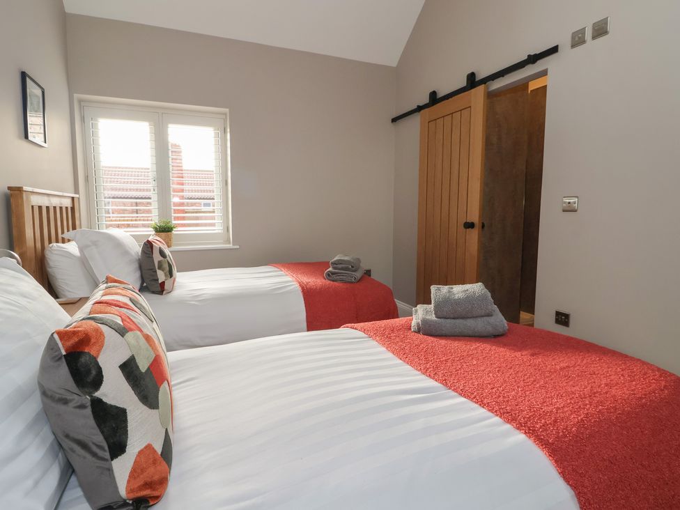 A bedroom with two beds and a window at Stable End Cottage Cuckoo Nest Farm near Wilberfoss