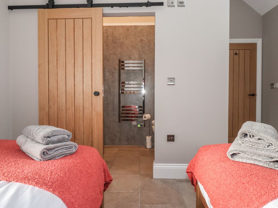 A bedroom with two beds and a bathroom at Stable End Cottage near Cuckoo Nest Farm near Wilberfoss