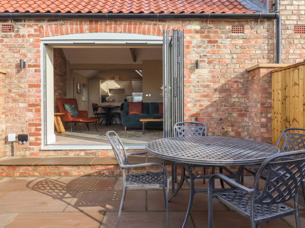 An outdoor patio with a table and chairs overlooking a kitchen at Stable End Cottage Cuckoo Nest Farm near Wilberfoss