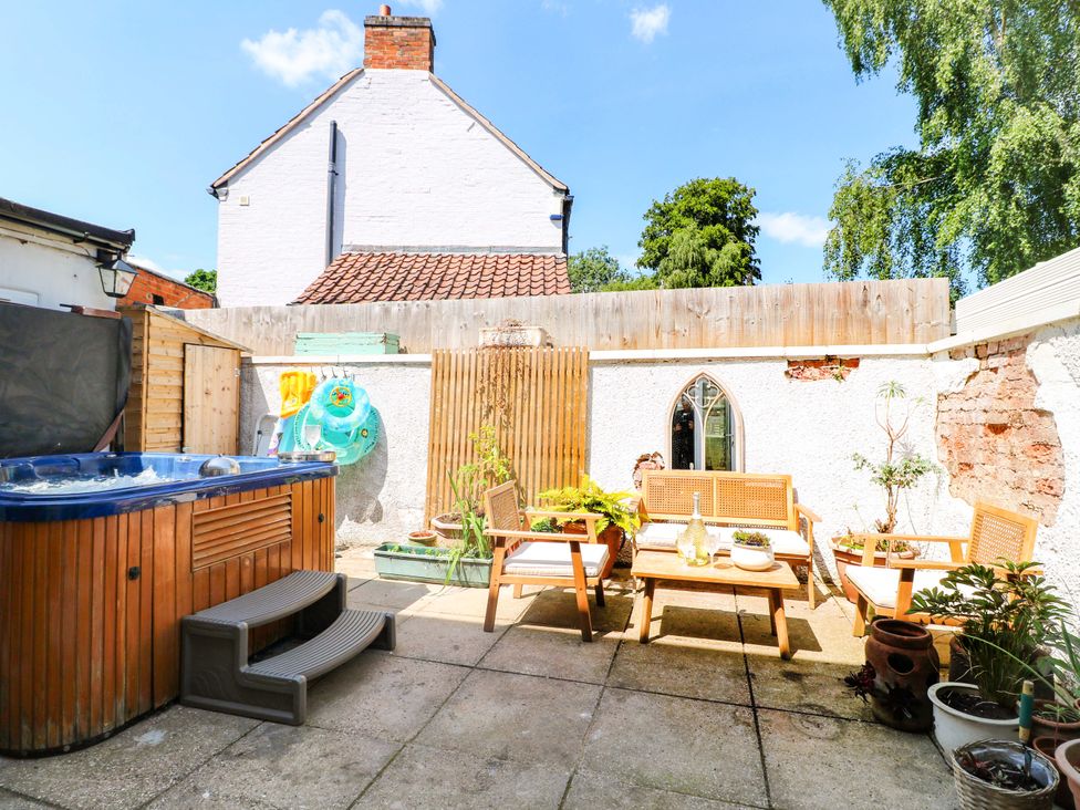 A garden with a hot tub and wooden seating at 83 Meeting Street Quorn