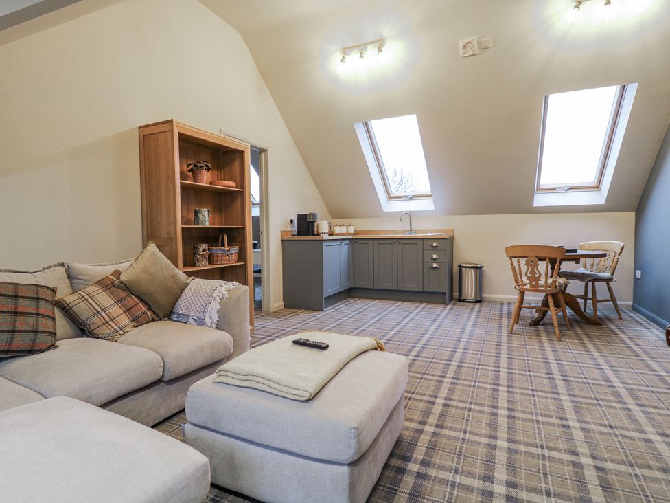 A living room with a sofa and kitchenette at The Walnut Room - Windmill Country Retreats Wymondham near Buckminster