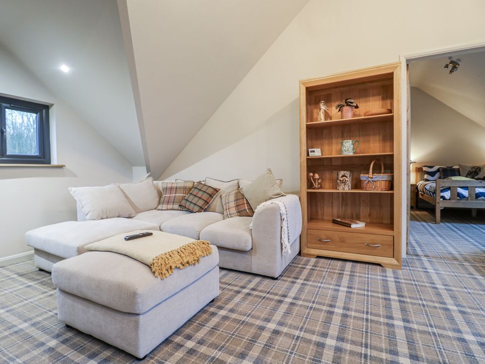 A snug with a sofa and bookshelf at The Walnut Room - Windmill Country Retreats in Wymondham near Buckminster