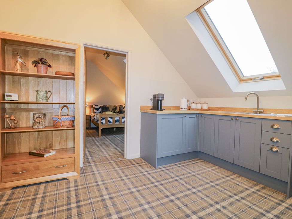 A studio with a kitchenette and bookshelf at The Walnut Room - Windmill Country Retreats Wymondham near Buckminster