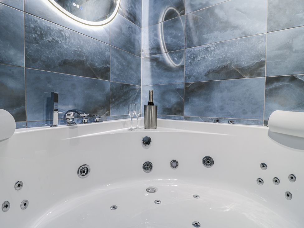 A bathroom with a hot tub and bottle in The Walnut Room - Windmill Country Retreats Wymondham near Buckminster