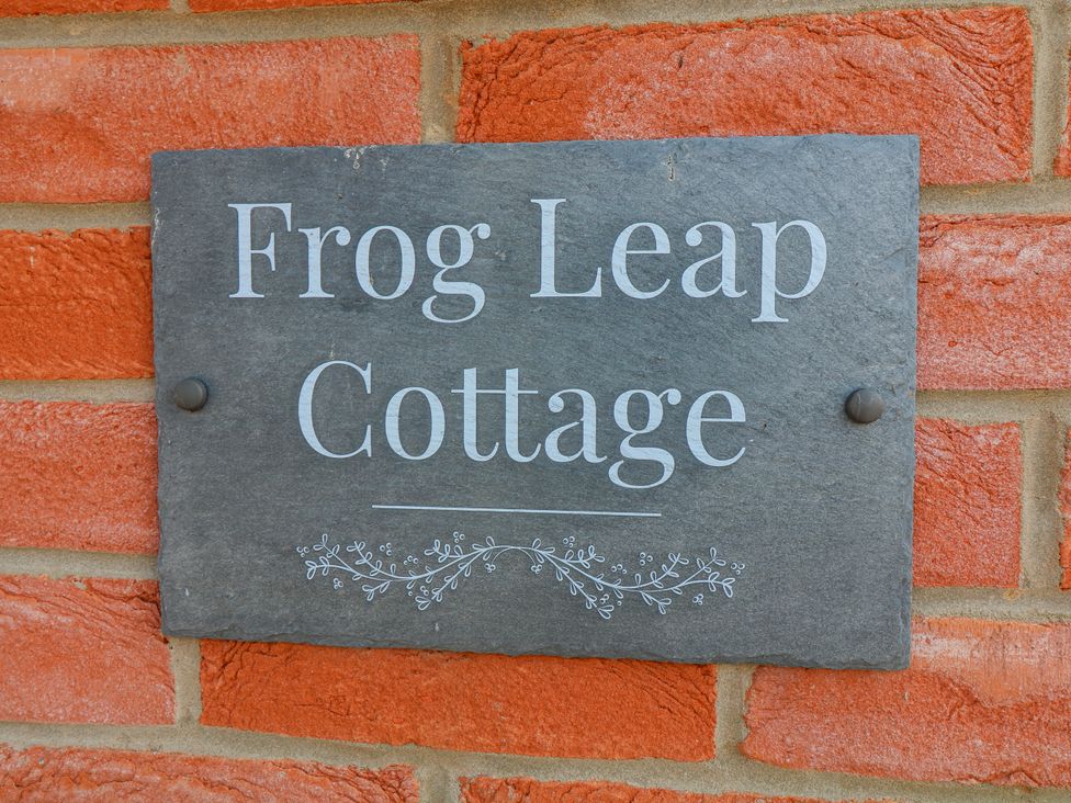 A slate sign with the text Frog Leap Cottage on a brick wall at Frog Leap, Scunthorpe
