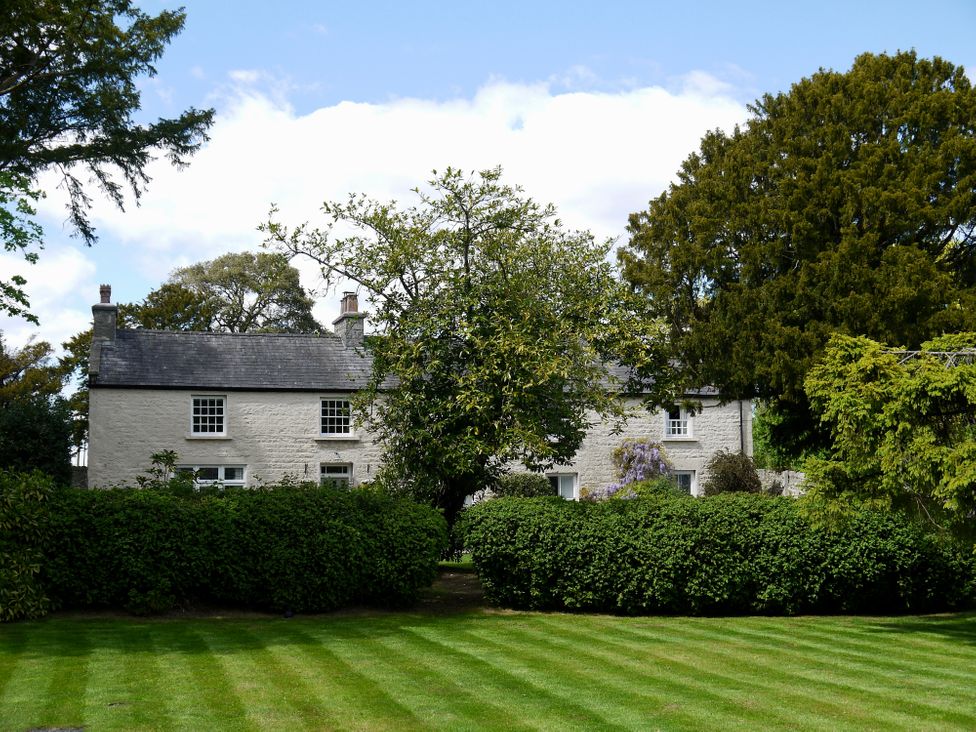 A house with a slate roof behind hedges and trees at 1 The Green in Silverdale