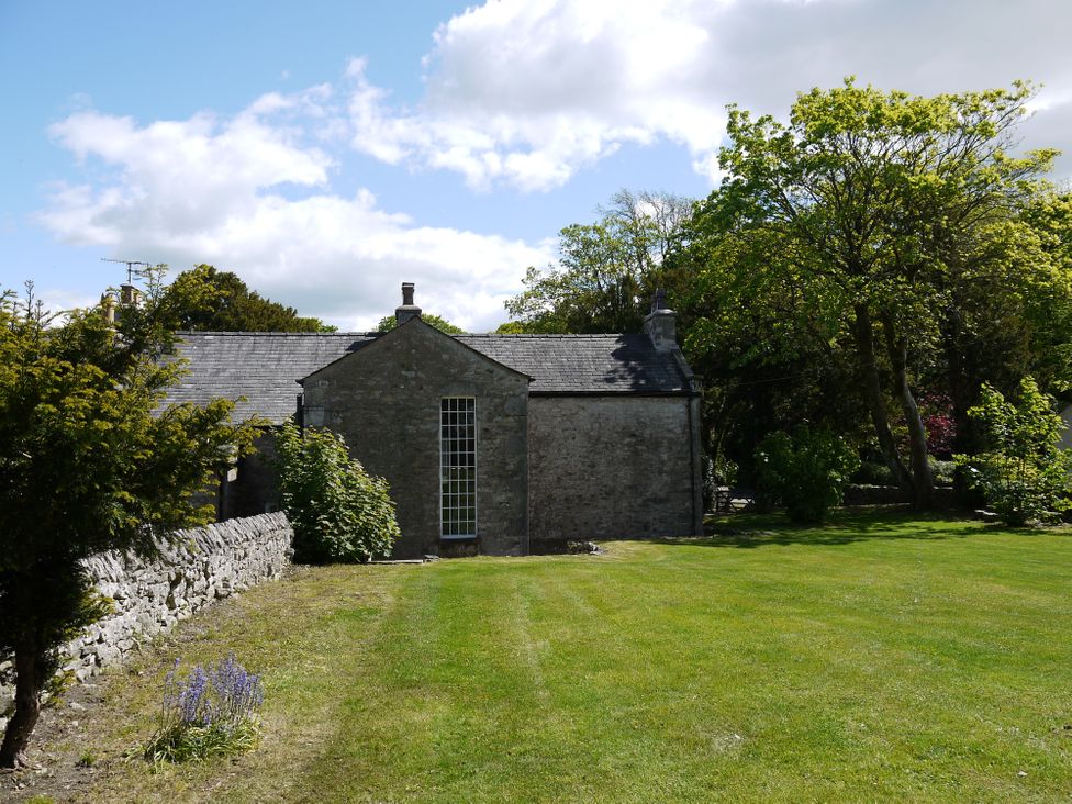 A stone building with a lawn and trees beside it at 1 The Green in Silverdale
