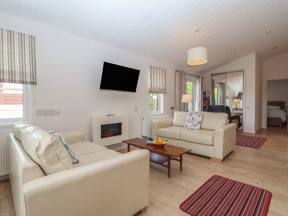 A living room with a sofa and television at Newton Calm in Newton Ferrers