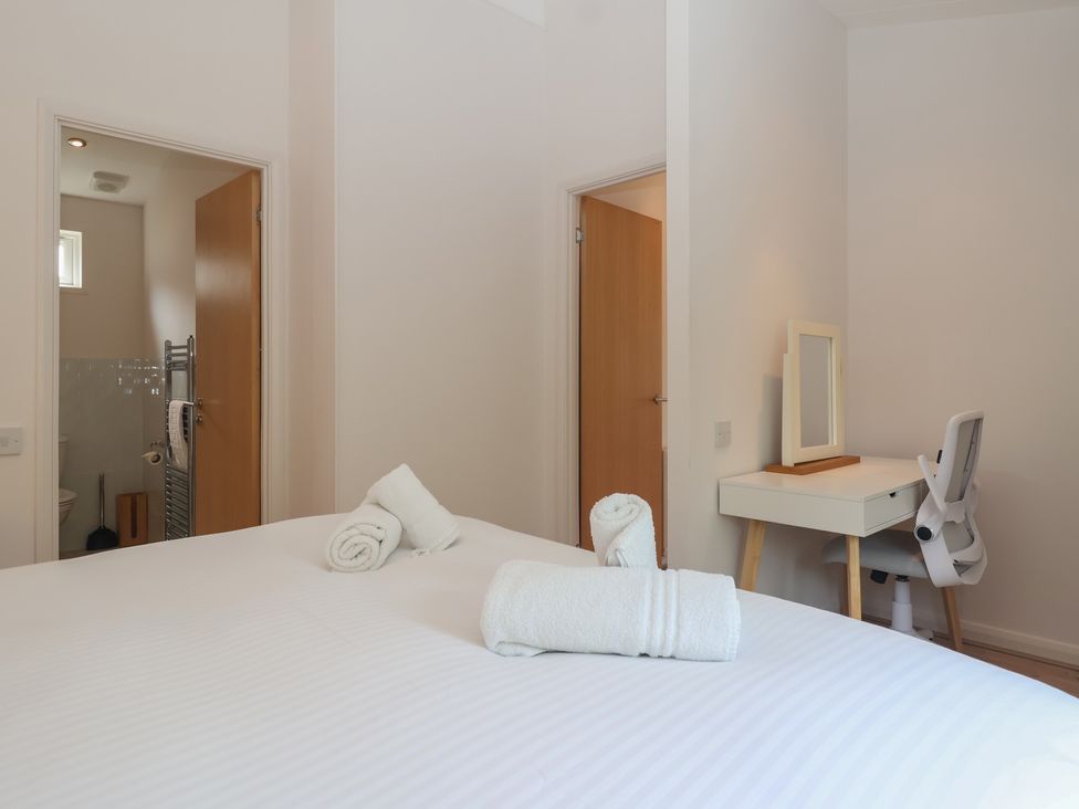 A bedroom with a bed, desk, and towels at Newton Calm in Newton Ferrers