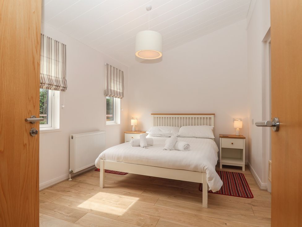 A bedroom with a bed and nightstands at Newton Calm in Newton Ferrers