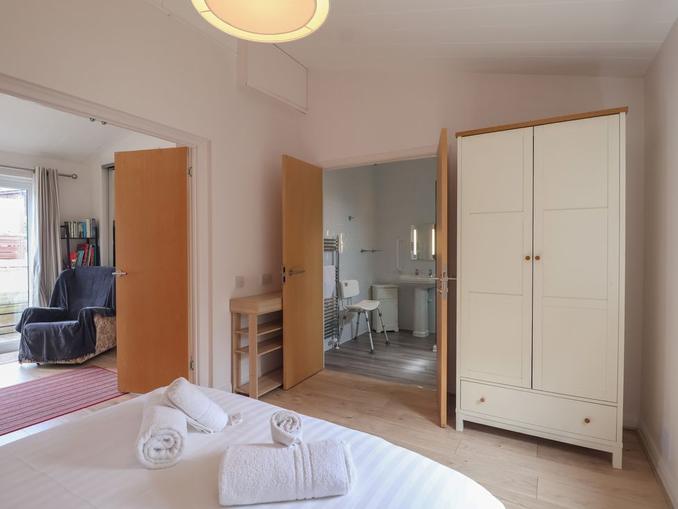 A bedroom with a wardrobe and bathroom door at Newton Calm in Newton Ferrers
