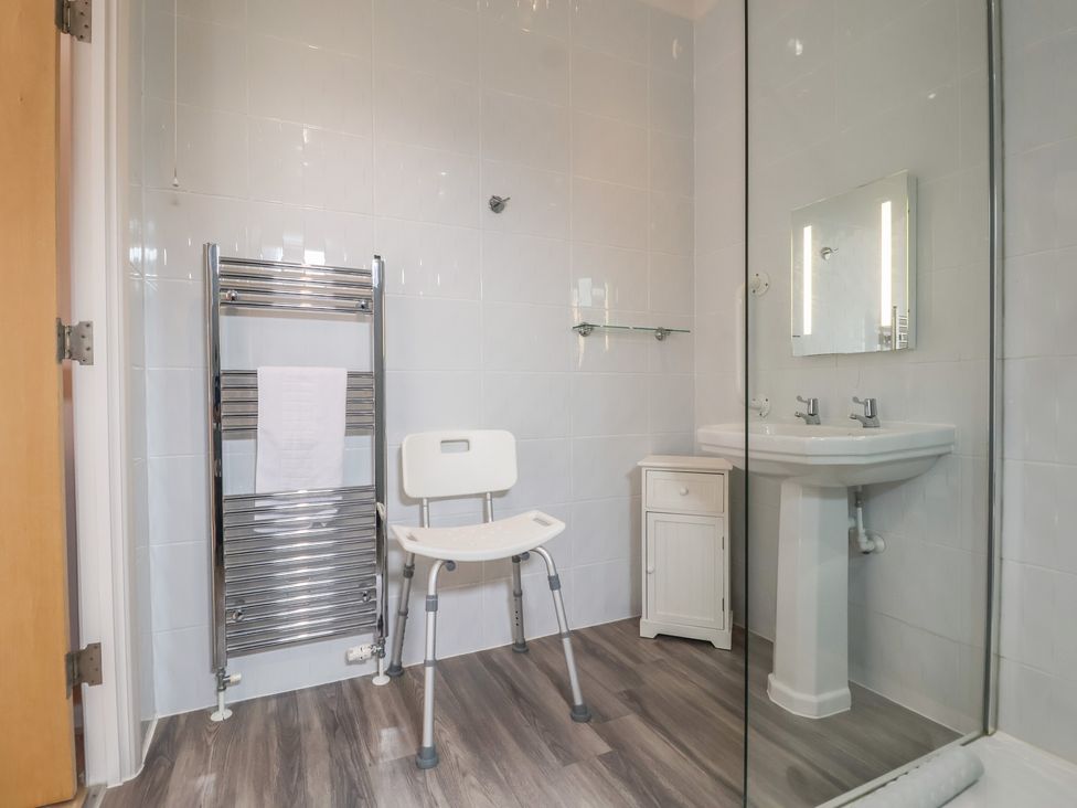 A bathroom with a shower, sink, towel rail, and cabinet at Newton Calm in Newton Ferrers