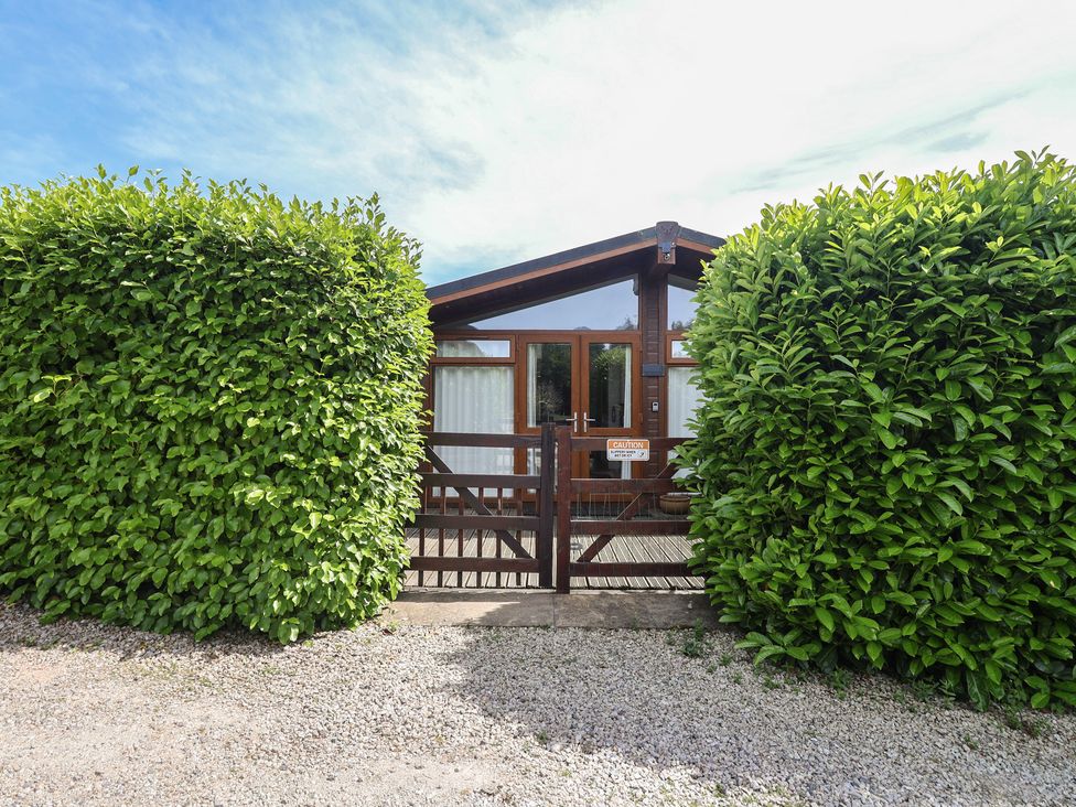 An outdoor view of a property with a gate and shrubs at Newton Calm in Newton Ferrers