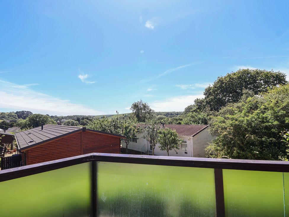 A view from a balcony showing houses and trees at Skyview in Newton Ferrers