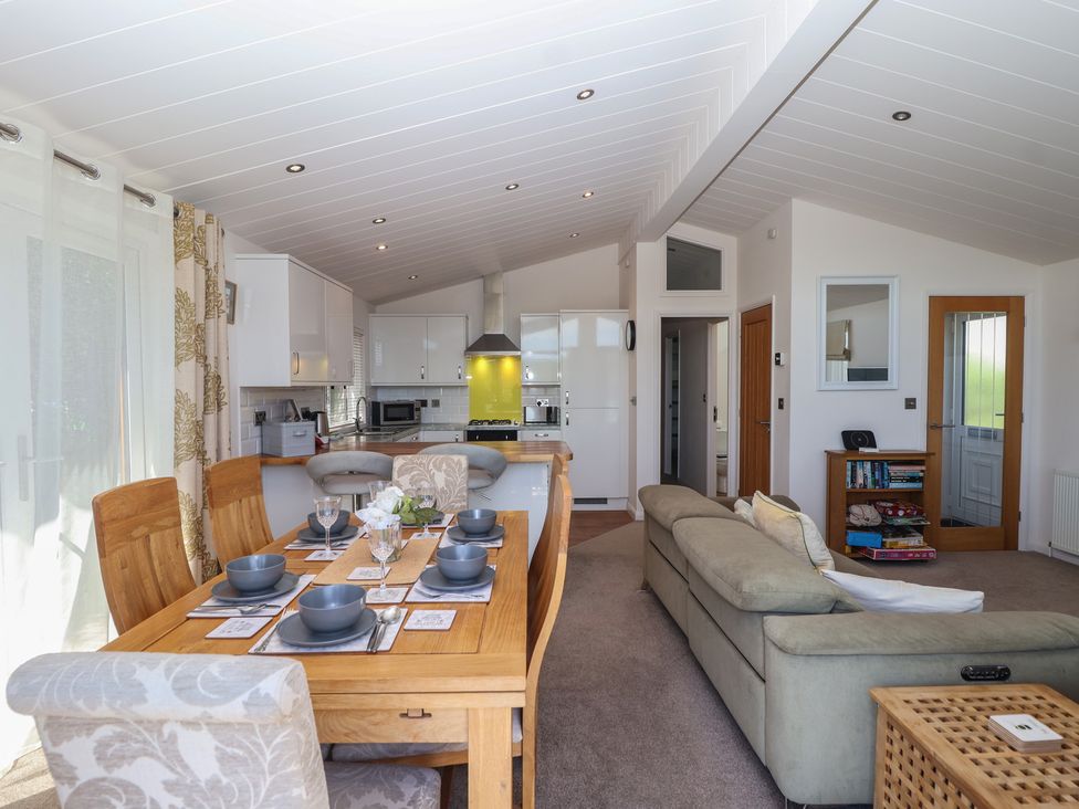 An open plan living and dining area with a table and kitchen at Skyview in Newton Ferrers