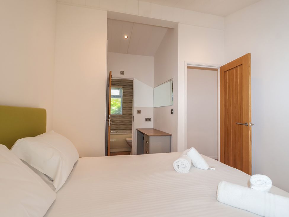 A bedroom with a bed and a door leading to a bathroom at Skyview in Newton Ferrers
