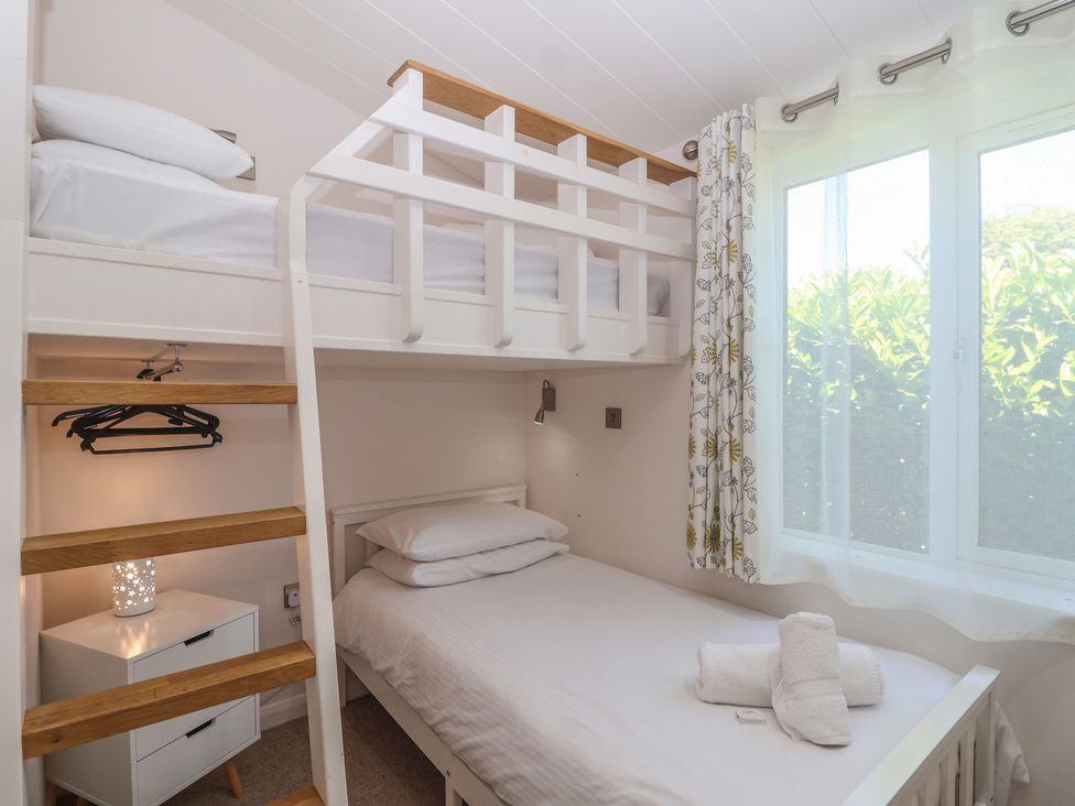 A bedroom with a bunk bed and a single bed at Skyview in Newton Ferrers