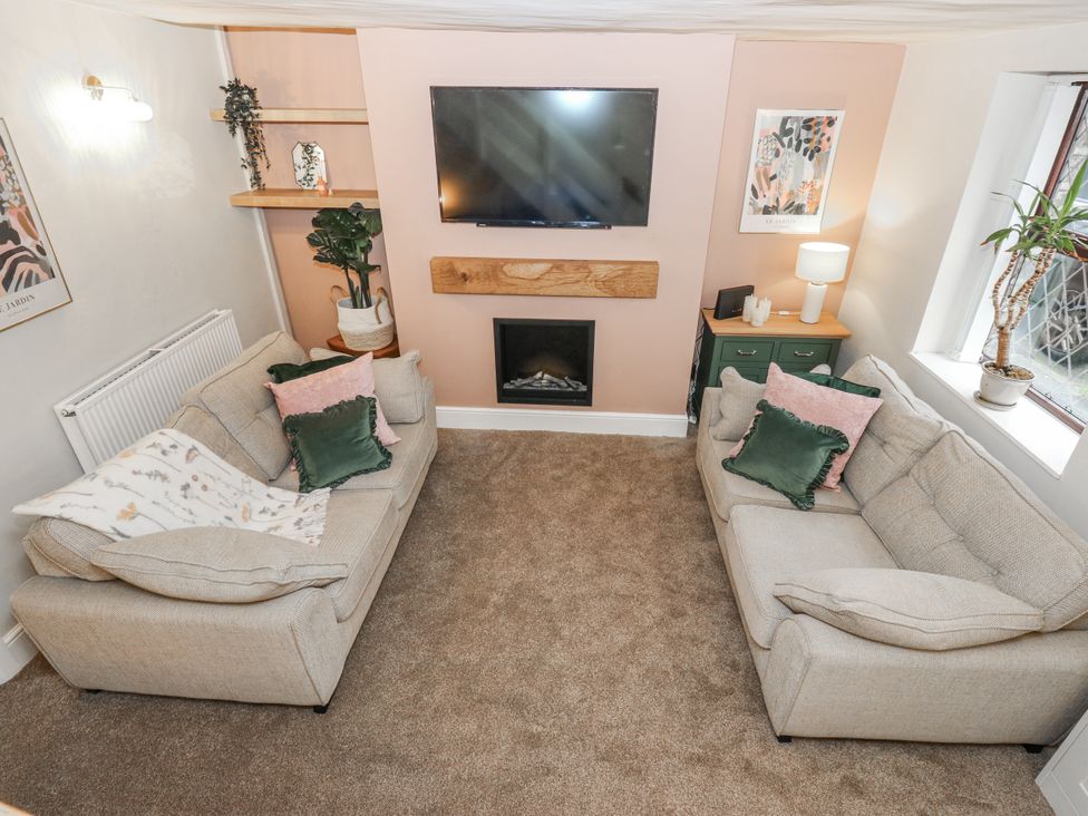 A living room with a television and fireplace at Court Street Cottage Uppermill