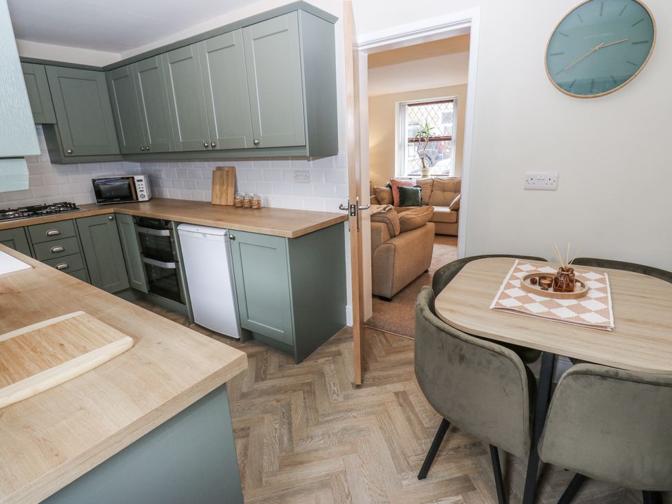 A kitchen with cabinets and table at Court Street Cottage in Uppermill