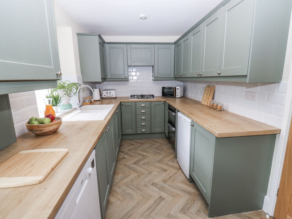 A kitchen with cabinets and appliances at Court Street Cottage, Uppermill