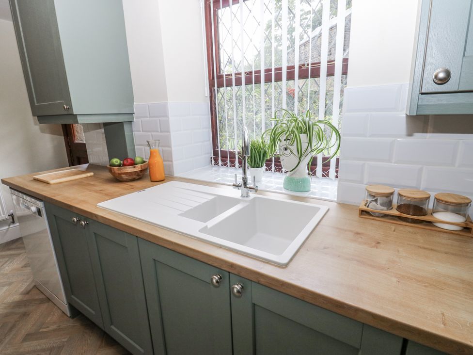 A kitchen with a sink and wooden countertop at Court Street Cottage Uppermill
