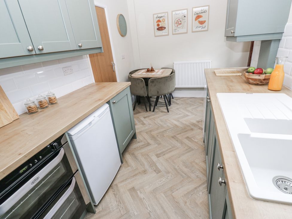 A kitchen with cabinets and a dining table at Court Street Cottage, Uppermill