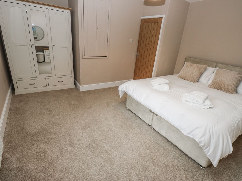 A bedroom with a bed and wardrobe at Court Street Cottage Uppermill