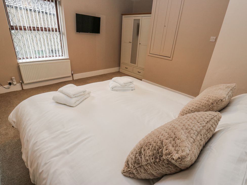 A bedroom with a bed and wardrobe at Court Street Cottage Uppermill
