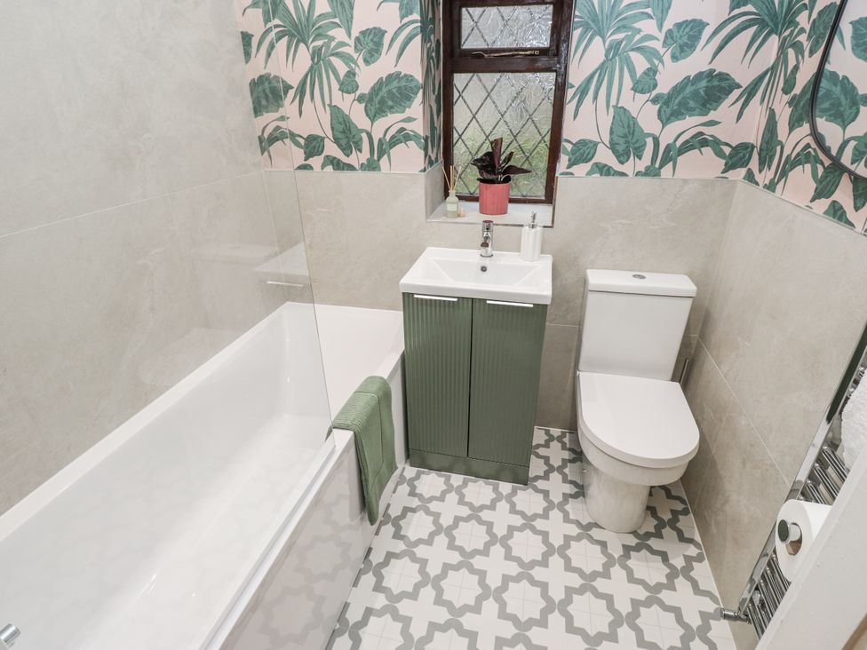 A bathroom with a bathtub, toilet, and sink at Court Street Cottage, Uppermill