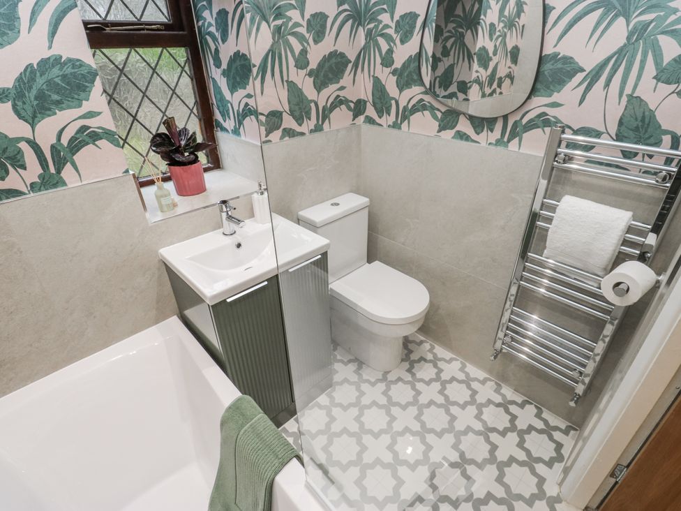 A bathroom with a bathtub, toilet, and washbasin at Court Street Cottage Uppermill
