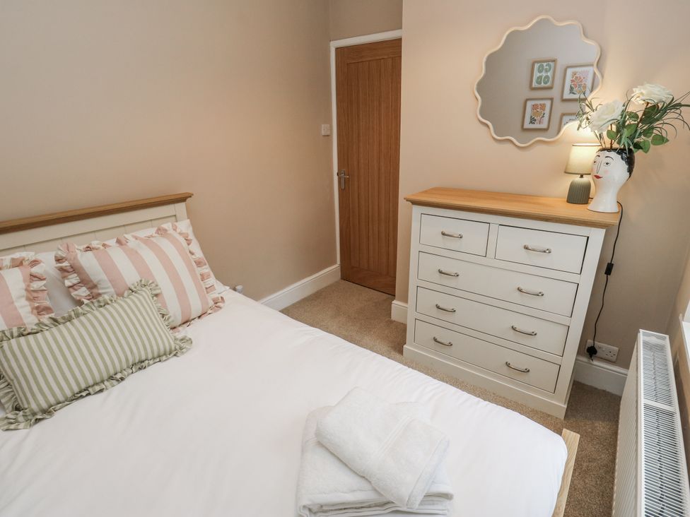 A bedroom with a bed and dresser at Court Street Cottage Uppermill