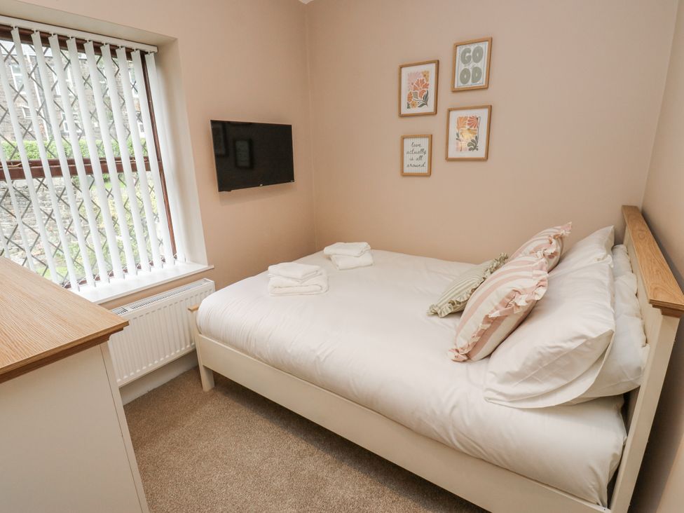A bedroom with a bed and a television at Court Street Cottage, Uppermill