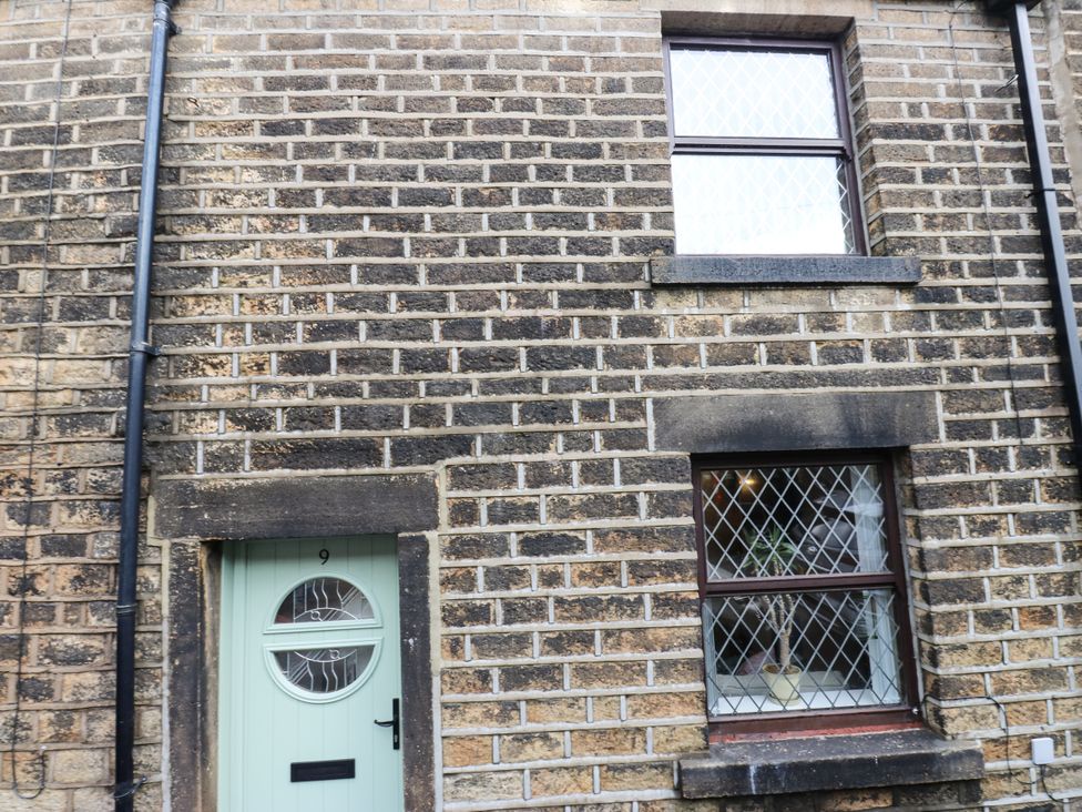 An outdoor view of a house exterior with a door and window at Court Street Cottage Uppermill