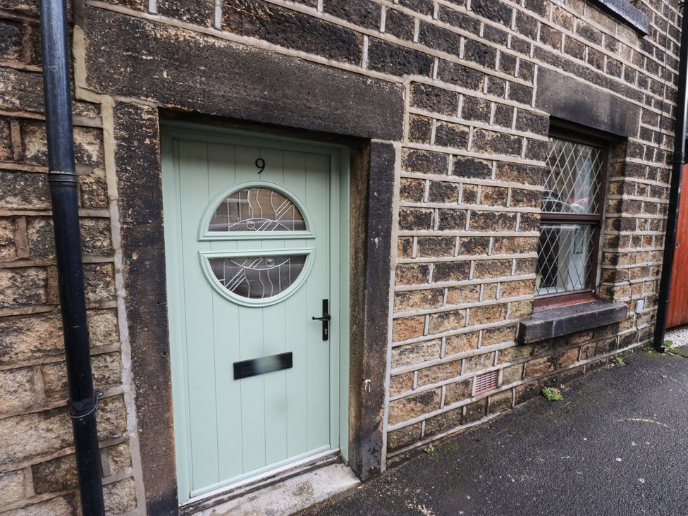 An entrance door with number 9 beside a brick wall at Court Street Cottage Uppermill