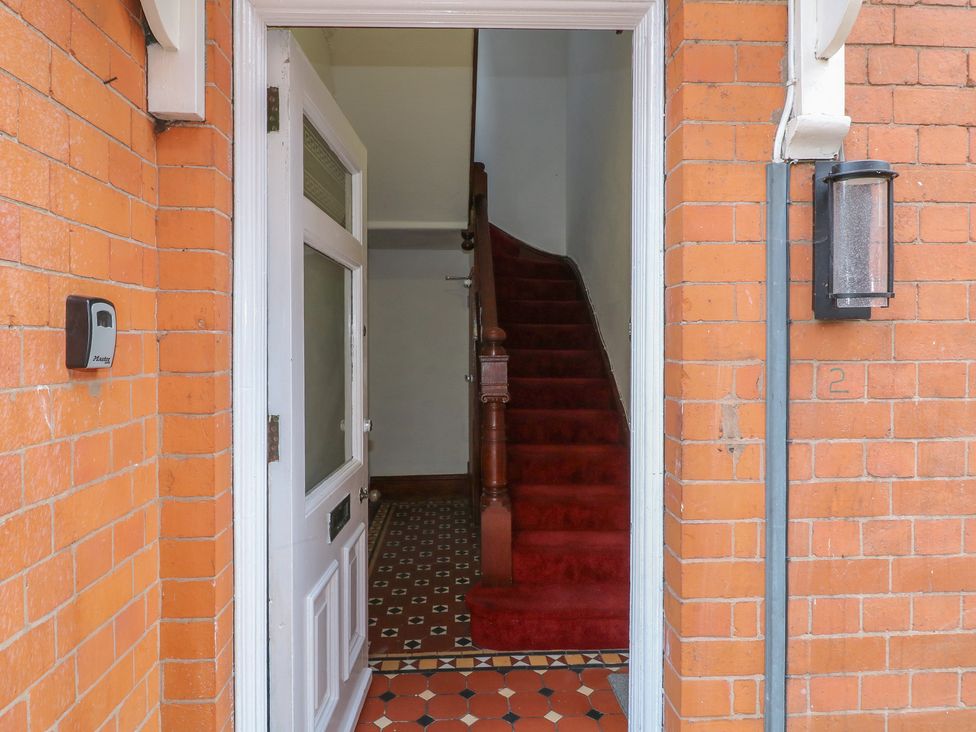 A hallway with a front door and staircase at 2 Evington Road