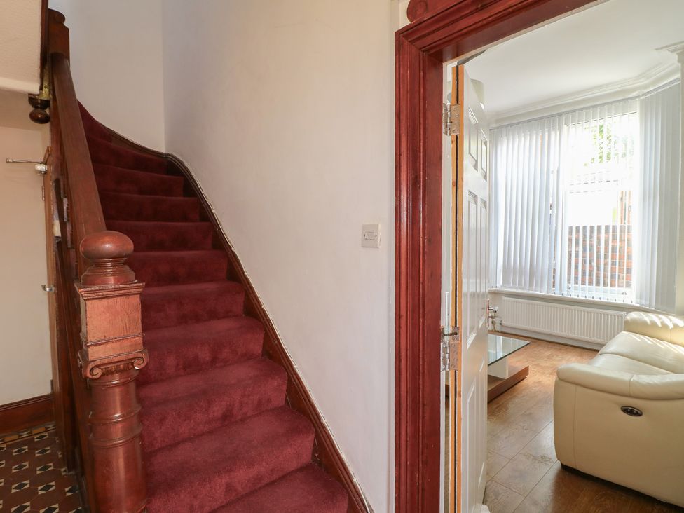 A hallway with stairs and a view into a living room at 2 Evington Road