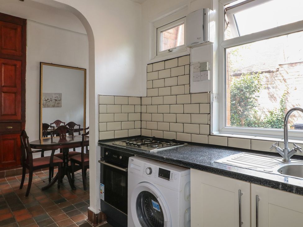 A kitchen with a stove, washing machine, and dining table at 2 Evington Road