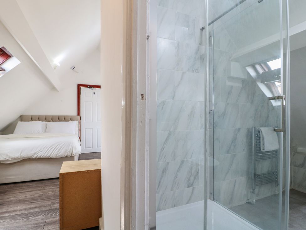 A bathroom with a shower and a bed visible at 2 Evington Road