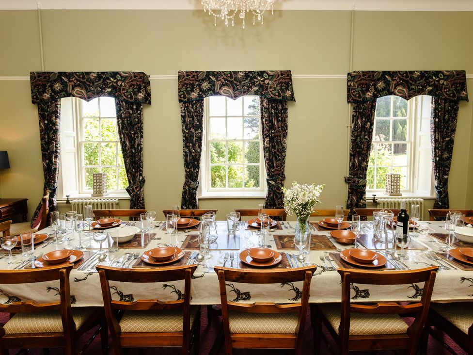 A dining room with a long table set for a meal at Cheviot Manor near Wooler