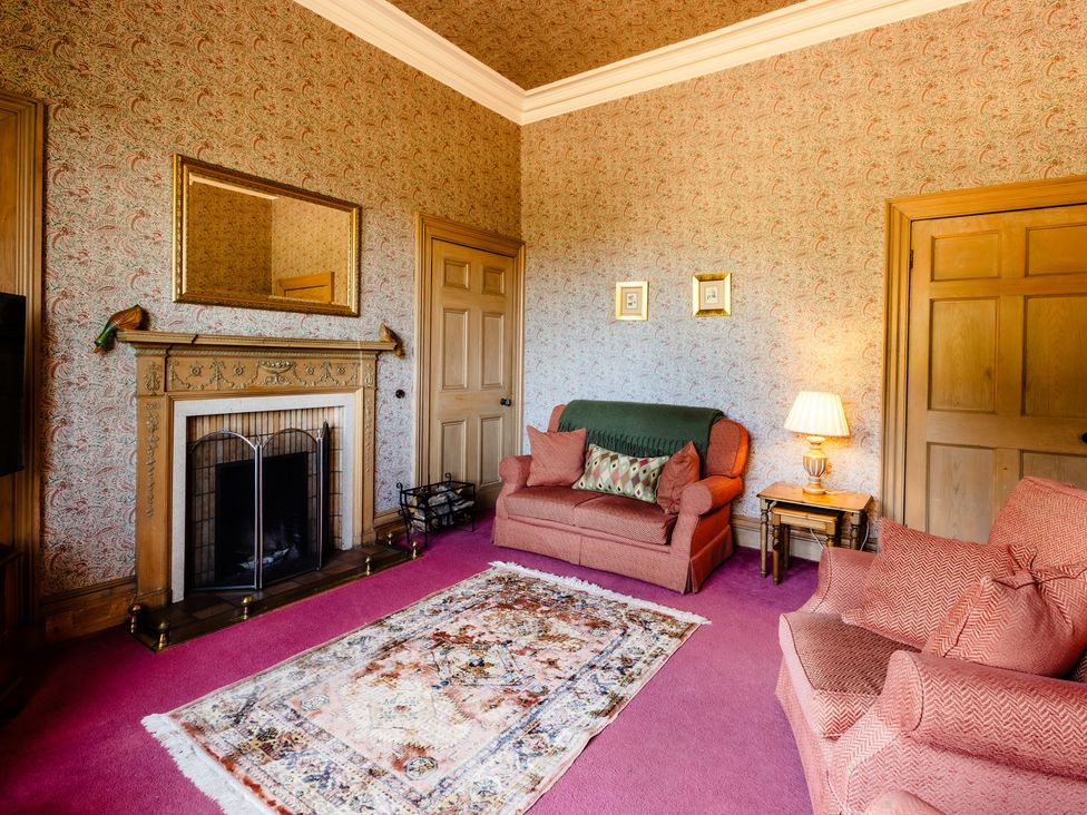 A living room with a fireplace and sofa at Cheviot Manor Akeld near Wooler
