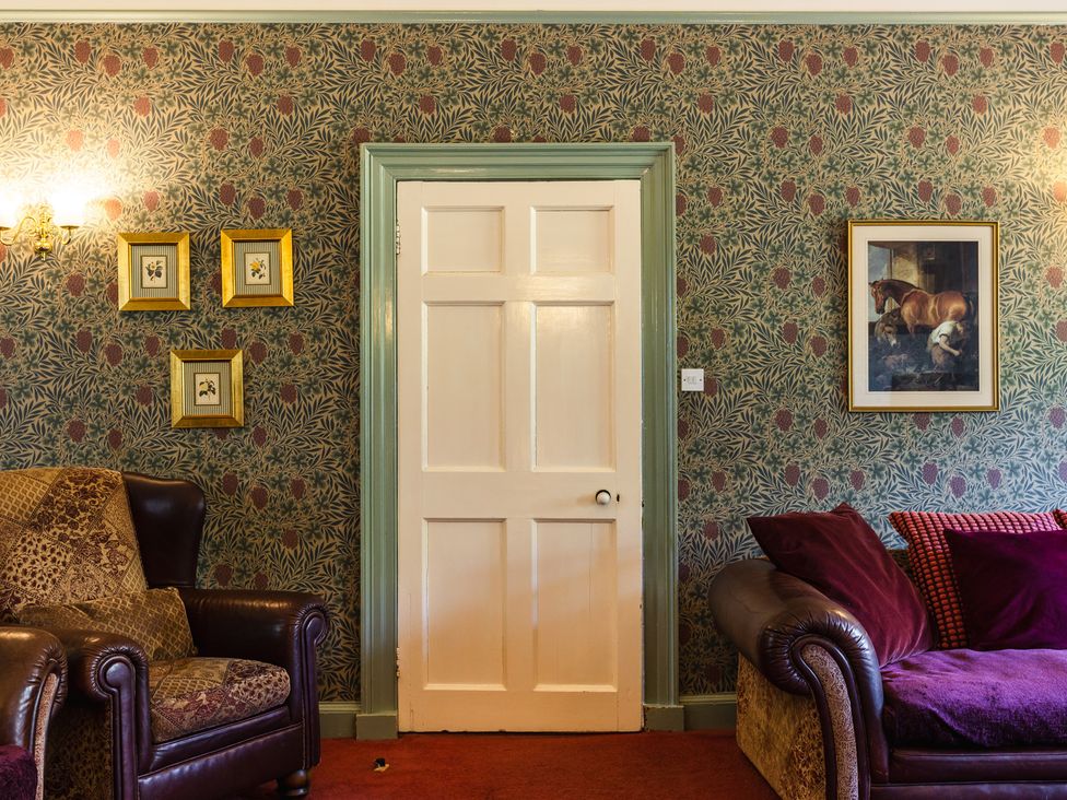 A living room with a door and framed paintings at Cheviot Manor Akeld near Wooler