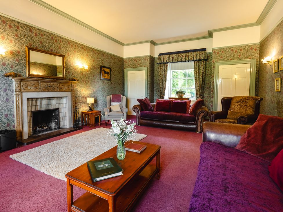 A living room with a fireplace and seating area at Cheviot Manor near Wooler