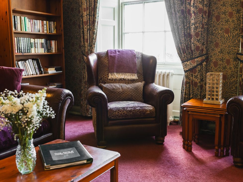 A living room with an armchair and bookshelf at Cheviot Manor in Akeld near Wooler