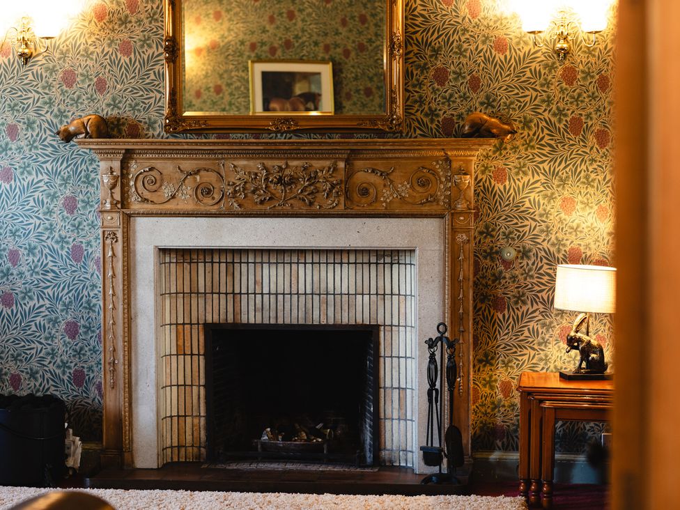 A living room with a fireplace and a mirror at Cheviot Manor in Akeld near Wooler